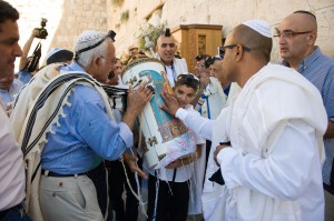 A 13-year-old Jewish boy carries the Torah scroll at the Western (Wailing) Wall as the adults venerate the Torah by kissing the Torah tik (ornate box protecting the Torah scroll).