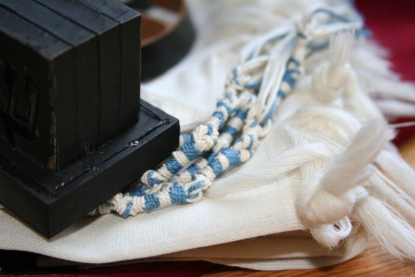 The black box of tefillin (which contains Scripture) and the tzitzit with the tekhelet (blue thread) of the tallit.