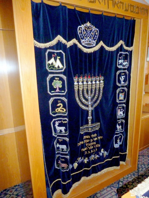The parokhet that today covers the Torah Ark represents the Parokhet that once hung at the entrance to the Holy of Holies where the Ark of the Covenant was held. This parokhet is embroidered with symbols of the Tribes of Israel and with the Menorah.