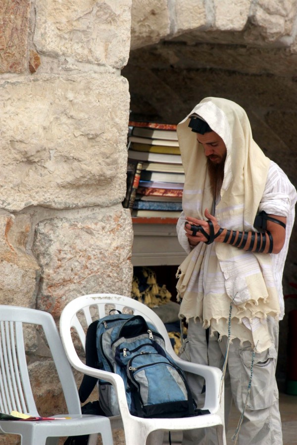 A Jewish man wearing a tallit (prayer shawl) and tefillin (phylacteries) prays at the Western Wall in Jerusalem.