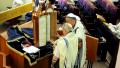 Reading from a Torah scroll encased in a protective Torah tik (case).