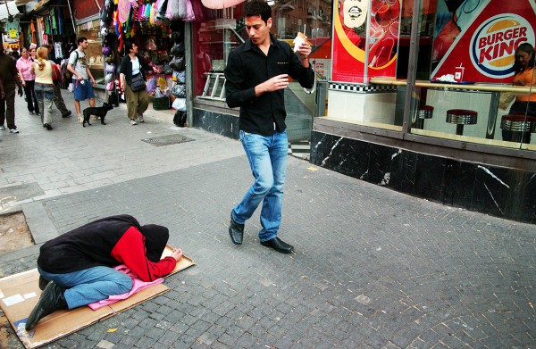 homeless man laying on busy sidewalk of Tel Aviv