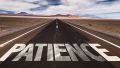 The word "patience" is written on a road that goes through the desert.