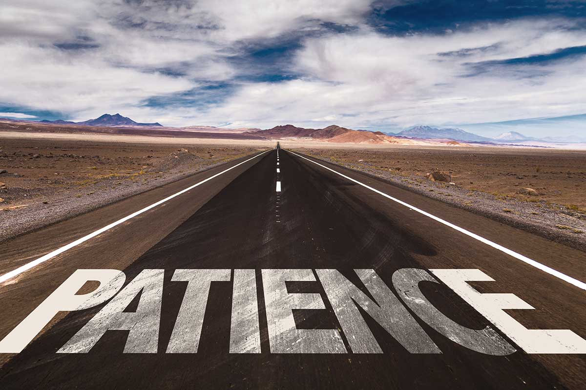 The word "patience" is written on a road that goes through the desert.